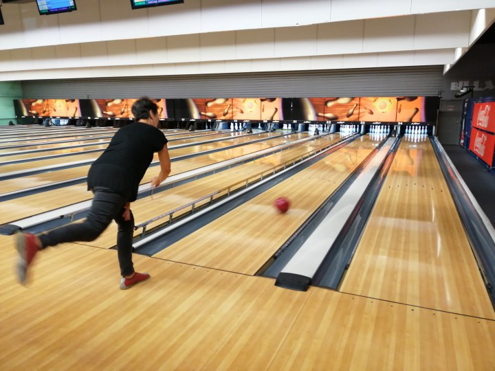 Une personne lance une boule sur la piste de Bowling.