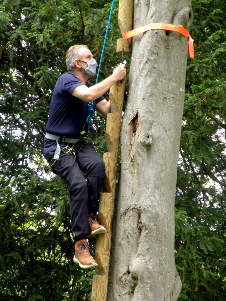 fabrice en pleine activité d'escalade où une partie d'un mur d'escalade est  installé contre un arbre