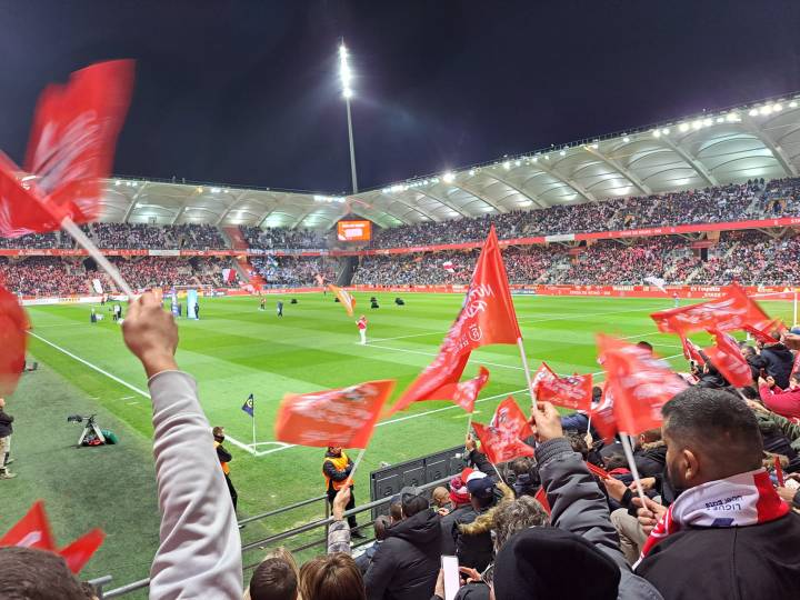 des drapeaux de supporter s'agitent au dessus de la pelouse du stade delaune
