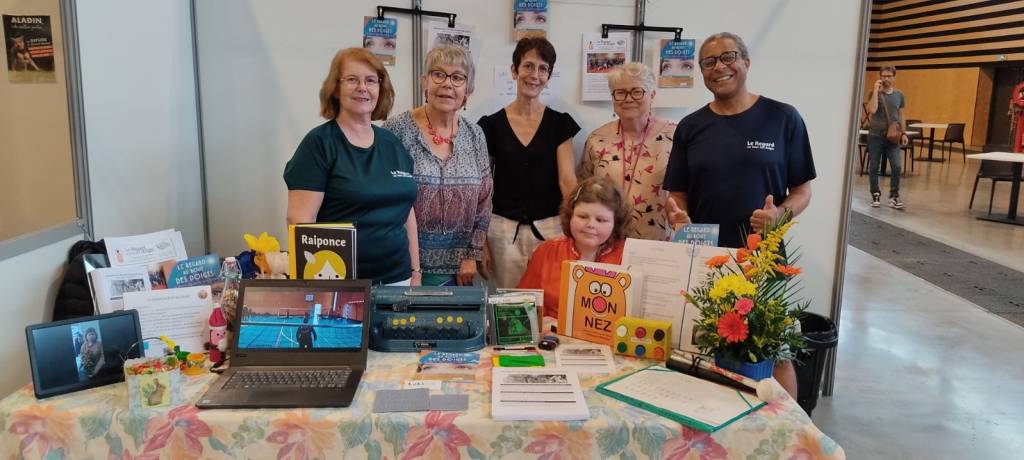 les membres du bureau et des adhérents au stand de l'asso
on voit des livres en braille des lunettes une perkins et des flyers