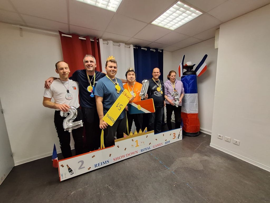 des joueurs prennent la pause sur un podium. ils ont des couronnes sur la tete. ils sont en binome sur les marches du podium