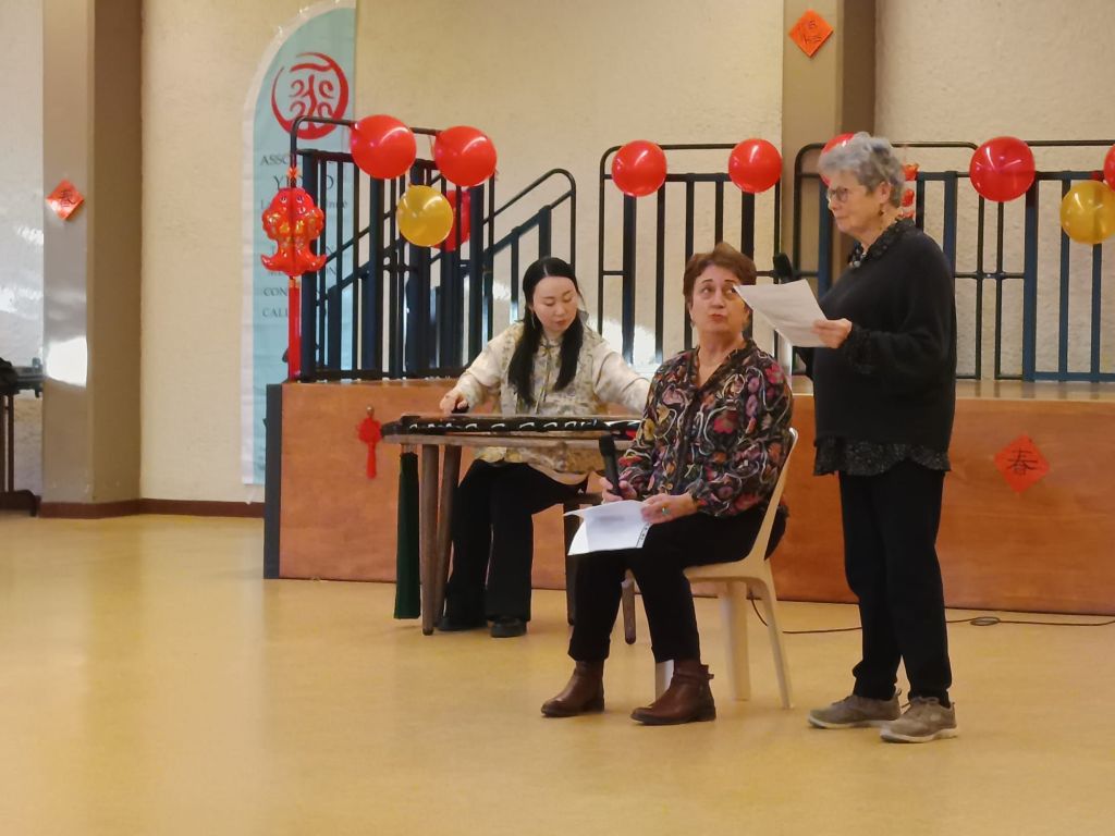 une personne joue d'un instrument et une autre lit un poème