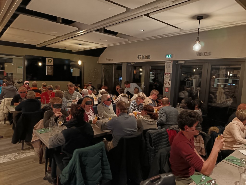une salle de restaurant avec une quarantaine de personnes yeux bandés